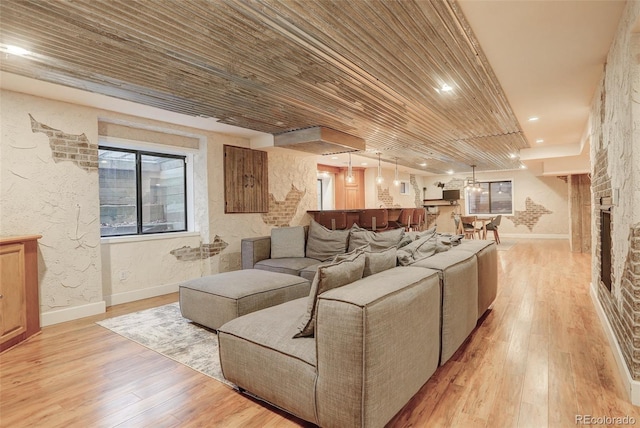 living room featuring wooden ceiling, light wood finished floors, baseboards, and a textured wall