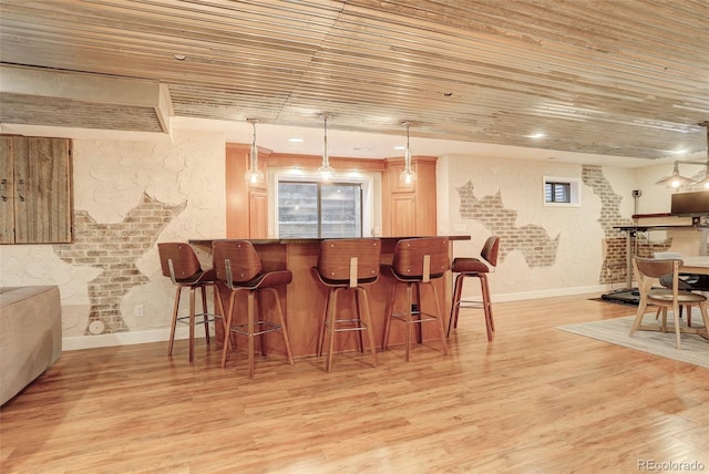 bar with hanging light fixtures, light wood-style flooring, wood ceiling, and a bar