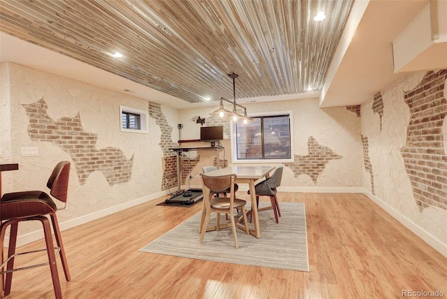 dining room featuring brick wall, wood finished floors, wood ceiling, and baseboards