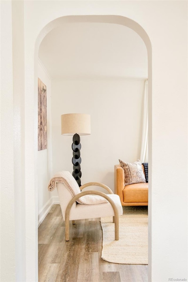 sitting room featuring arched walkways, wood finished floors, and baseboards