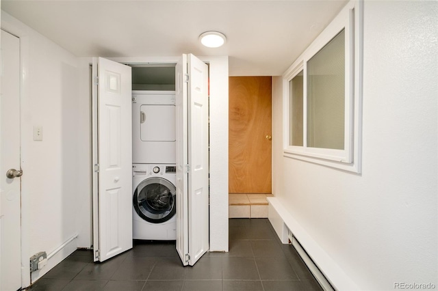 washroom featuring laundry area, dark tile patterned floors, and stacked washer and clothes dryer