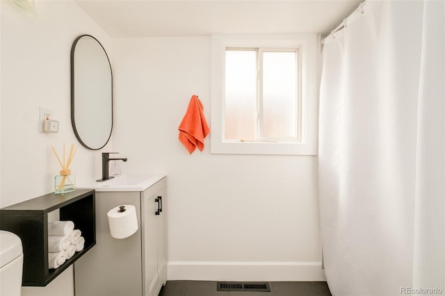 bathroom featuring toilet, vanity, visible vents, and baseboards