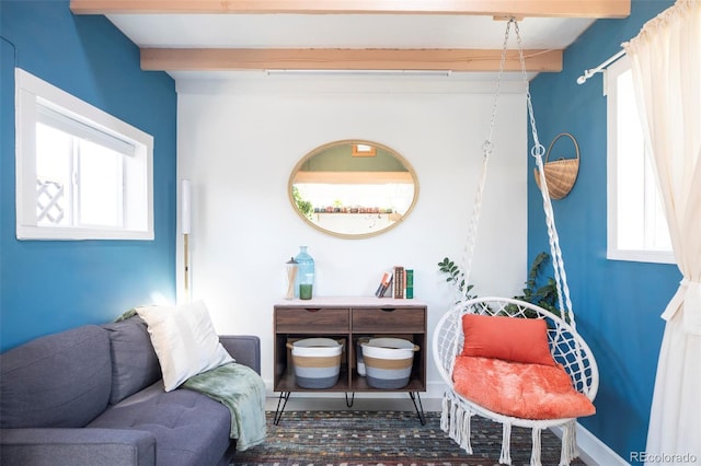 sitting room featuring beam ceiling and baseboards