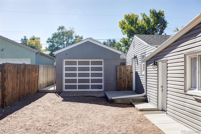 detached garage featuring fence and driveway