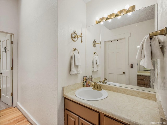bathroom featuring vanity, baseboards, and wood finished floors