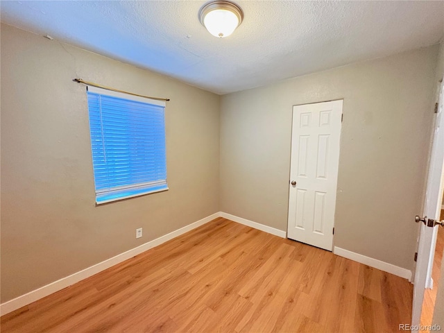 spare room featuring light hardwood / wood-style floors and a textured ceiling