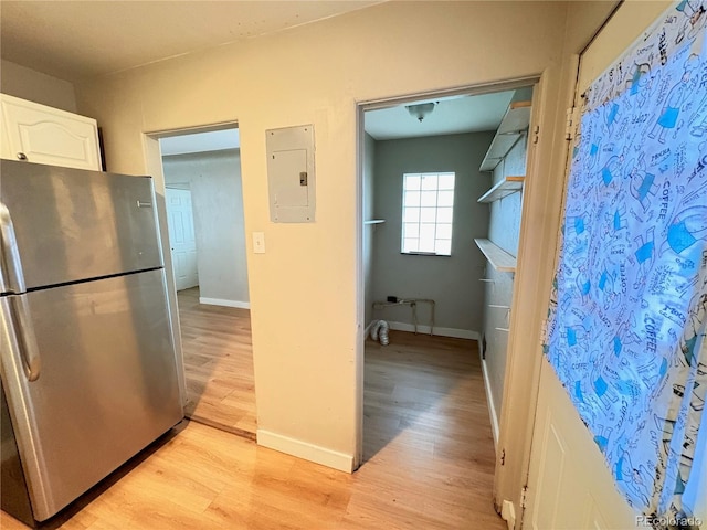 kitchen featuring white cabinets, stainless steel fridge, light wood-type flooring, and electric panel