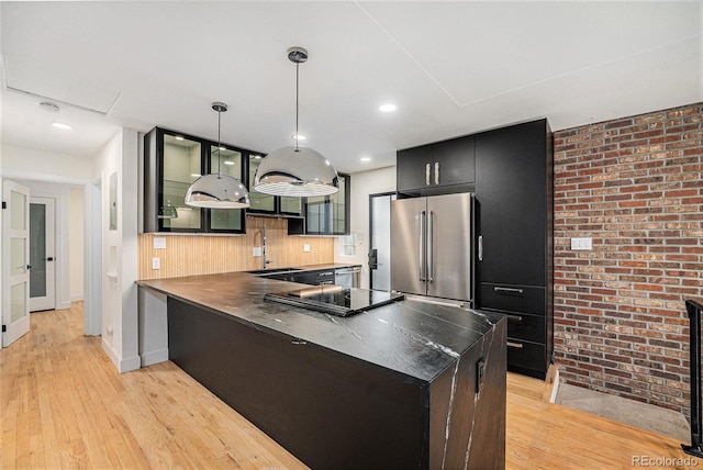 1111 Monroe St, Denver, CO 80206 - kitchen with appliances with stainless steel finishes, a peninsula, a sink, light wood-style flooring, and brick wall