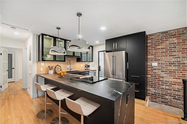 1111 Monroe St, Denver, CO 80206 - kitchen featuring high end refrigerator, brick wall, a sink, light wood-style flooring, and a kitchen bar