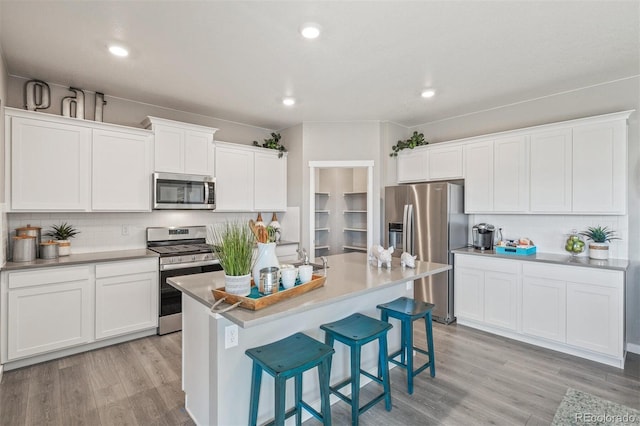 18150 Coppermallow Trl, Parker, CO 80134 - kitchen featuring stainless steel appliances, backsplash, light wood-type flooring, a breakfast bar area, and white cabinetry
