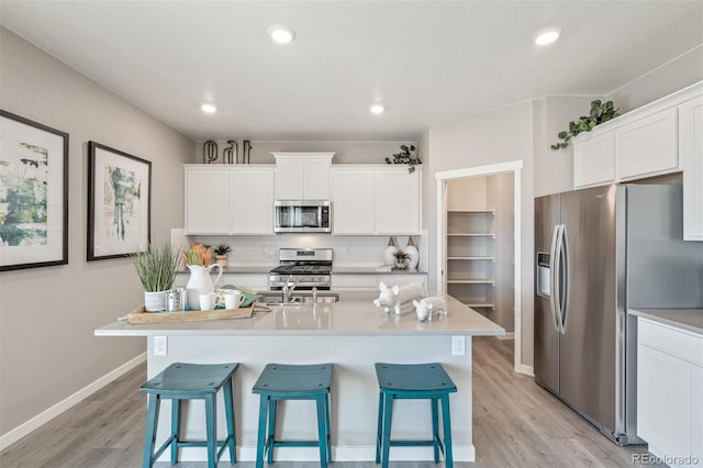18150 Coppermallow Trl, Parker, CO 80134 - kitchen featuring stainless steel appliances, light wood finished floors, a breakfast bar area, white cabinetry, and recessed lighting