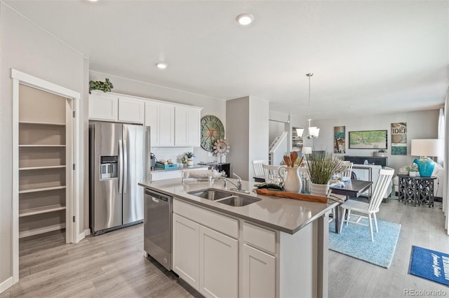18150 Coppermallow Trl, Parker, CO 80134 - kitchen featuring stainless steel appliances, a chandelier, white cabinetry, light wood-style flooring, and a kitchen island with sink