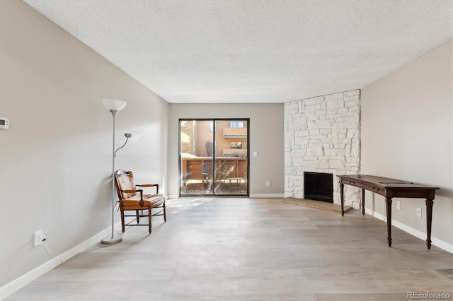 living room featuring light wood-type flooring, a textured ceiling, and a fireplace