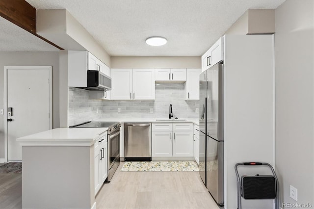 kitchen featuring appliances with stainless steel finishes, white cabinetry, sink, backsplash, and light hardwood / wood-style flooring