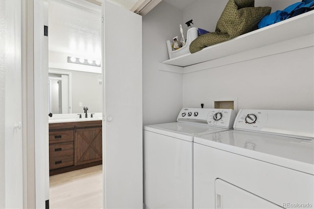 washroom with washer and dryer, sink, and light wood-type flooring