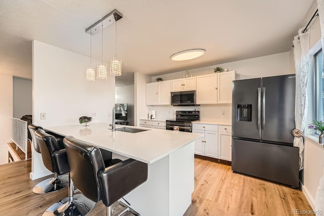 kitchen featuring decorative light fixtures, stainless steel fridge, sink, range with electric cooktop, and white cabinets