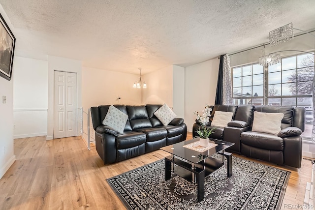 living room featuring an inviting chandelier, a textured ceiling, and light hardwood / wood-style flooring