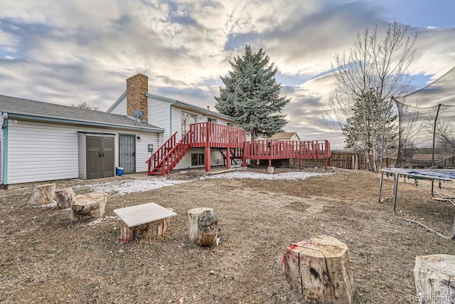 rear view of house with a trampoline and a wooden deck