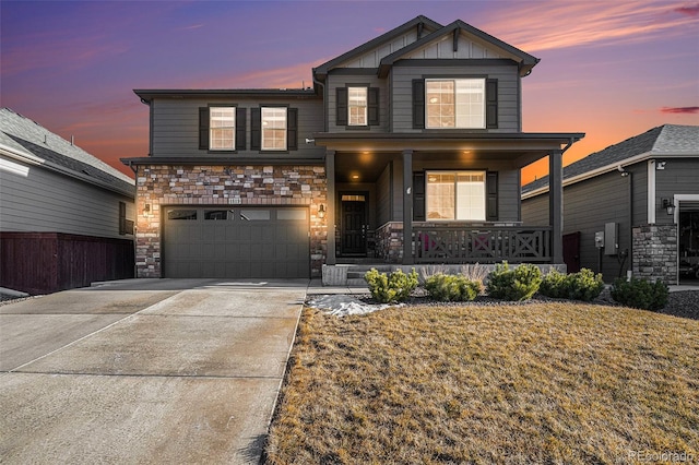 view of front of property with covered porch, concrete driveway, board and batten siding, a garage, and stone siding