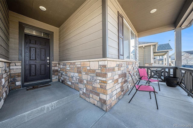 view of exterior entry featuring stone siding and a porch