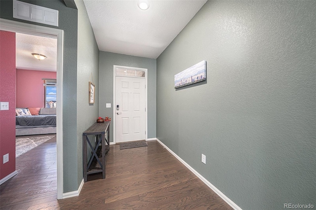 doorway to outside with visible vents, a textured ceiling, baseboards, and wood finished floors