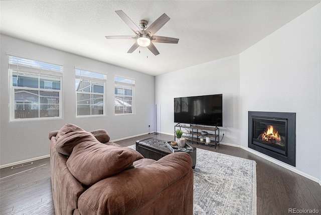 living room with baseboards, visible vents, wood finished floors, and a glass covered fireplace