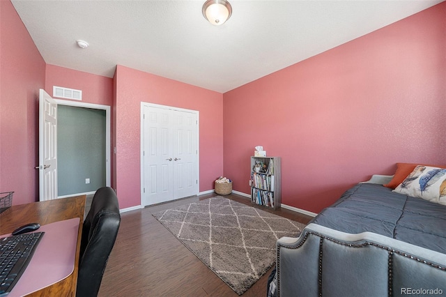 bedroom with a closet, visible vents, baseboards, and wood finished floors