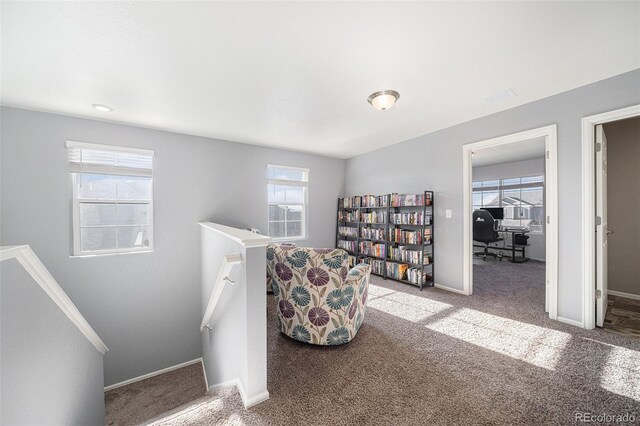 living area featuring baseboards, carpet flooring, and an upstairs landing