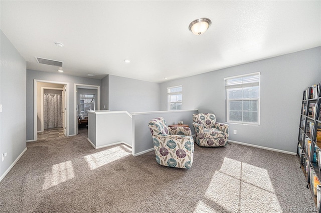 sitting room with carpet, baseboards, visible vents, and an upstairs landing