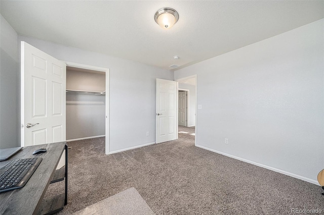 carpeted bedroom featuring a spacious closet, baseboards, and a closet