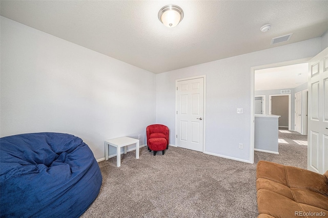 living area with carpet floors, visible vents, a textured ceiling, and baseboards