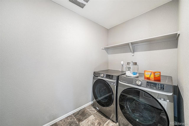 laundry room with laundry area, stone finish flooring, baseboards, and washer and dryer