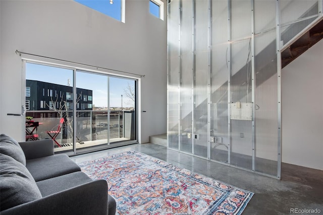 living room featuring concrete floors, a wealth of natural light, and a towering ceiling