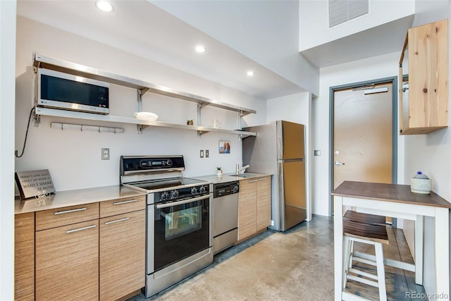 kitchen featuring recessed lighting, finished concrete flooring, visible vents, appliances with stainless steel finishes, and a sink