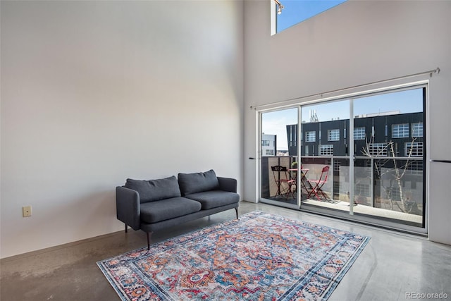 living area with a towering ceiling and concrete flooring