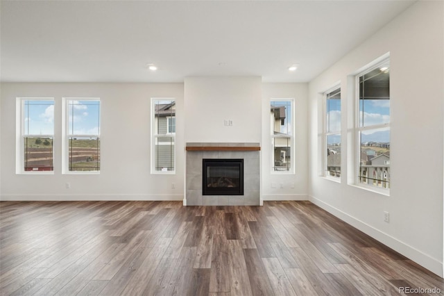 unfurnished living room featuring baseboards, recessed lighting, wood finished floors, and a tile fireplace