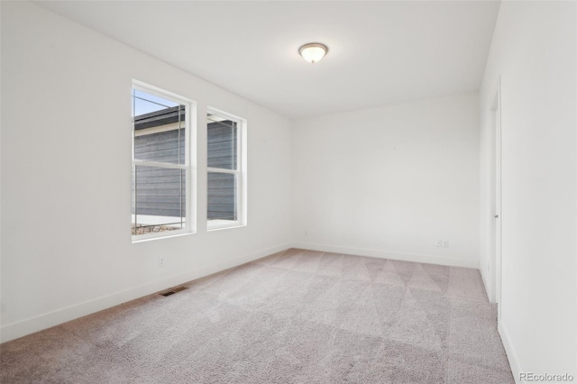 empty room featuring visible vents, baseboards, and light colored carpet