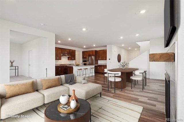 living area with recessed lighting, a fireplace, and light wood finished floors