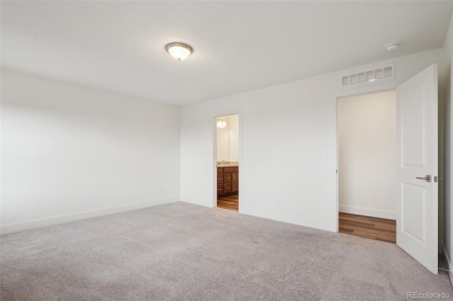 unfurnished bedroom featuring carpet floors, baseboards, visible vents, and connected bathroom