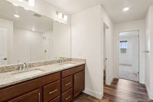 bathroom with baseboards, visible vents, a sink, and wood finished floors