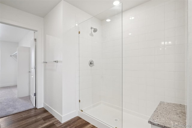 full bathroom featuring baseboards, wood finished floors, and tiled shower