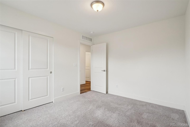 unfurnished bedroom with baseboards, visible vents, carpet, and a closet