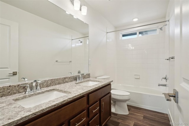 full bathroom with a sink, double vanity, toilet, and wood finished floors