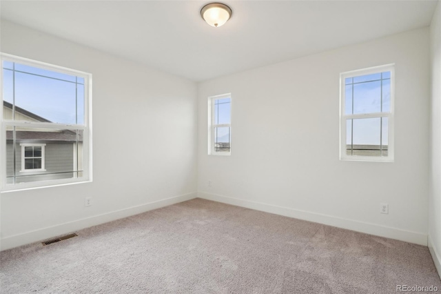 empty room featuring carpet floors, baseboards, and visible vents