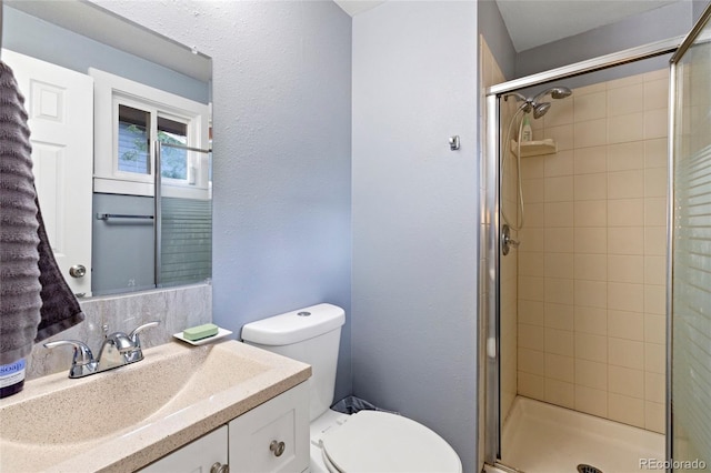 bathroom with vanity, a shower with door, and toilet