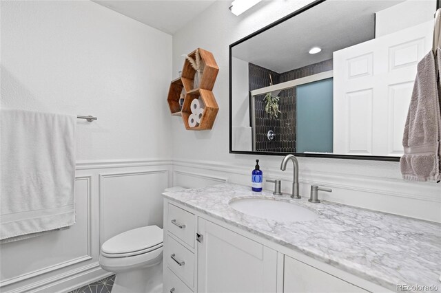 bathroom with vanity, a shower with door, and toilet