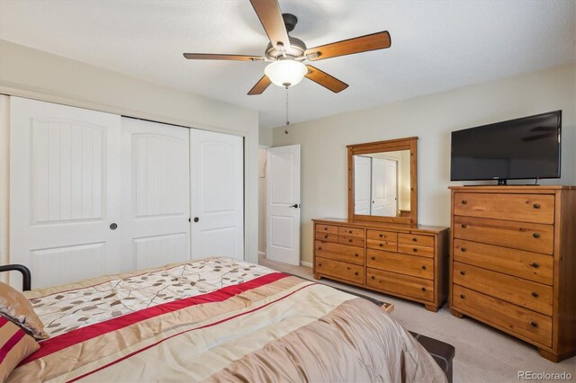 bedroom featuring light colored carpet, a closet, and a ceiling fan