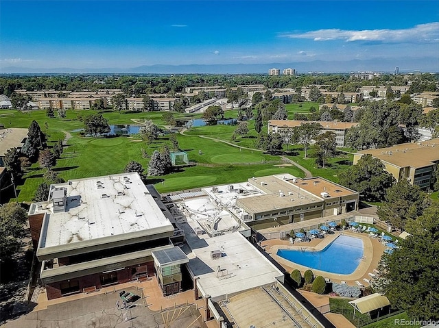 drone / aerial view of a nearby body of water, a pool, and a golf course