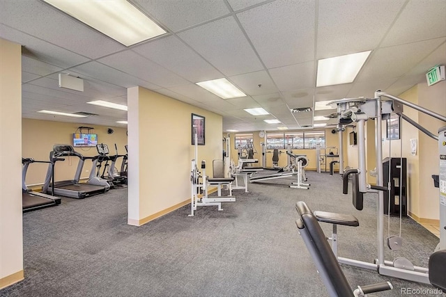 exercise room featuring a paneled ceiling, carpet flooring, and baseboards