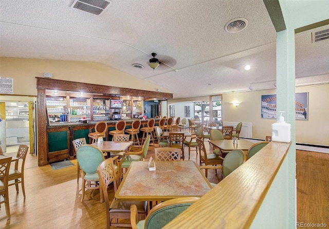 dining area with light wood-style floors, a textured ceiling, lofted ceiling, and recessed lighting